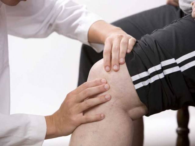 Врач ощупывает колено пациента